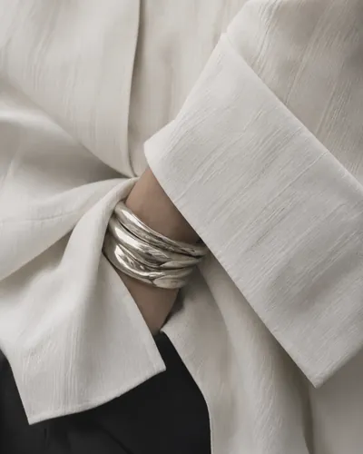 Silver cuffs at the wrist of a cream silk shirt