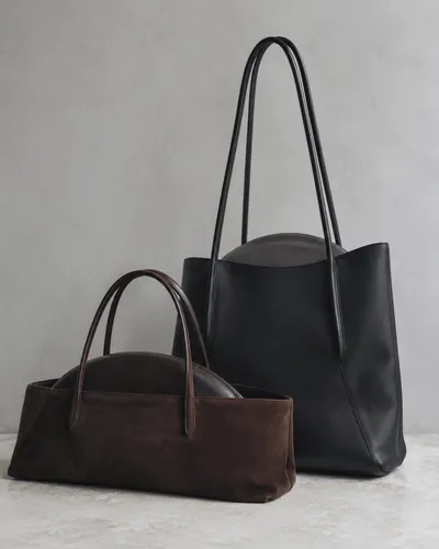 A tall black tote beside a brown suede shoulder bag